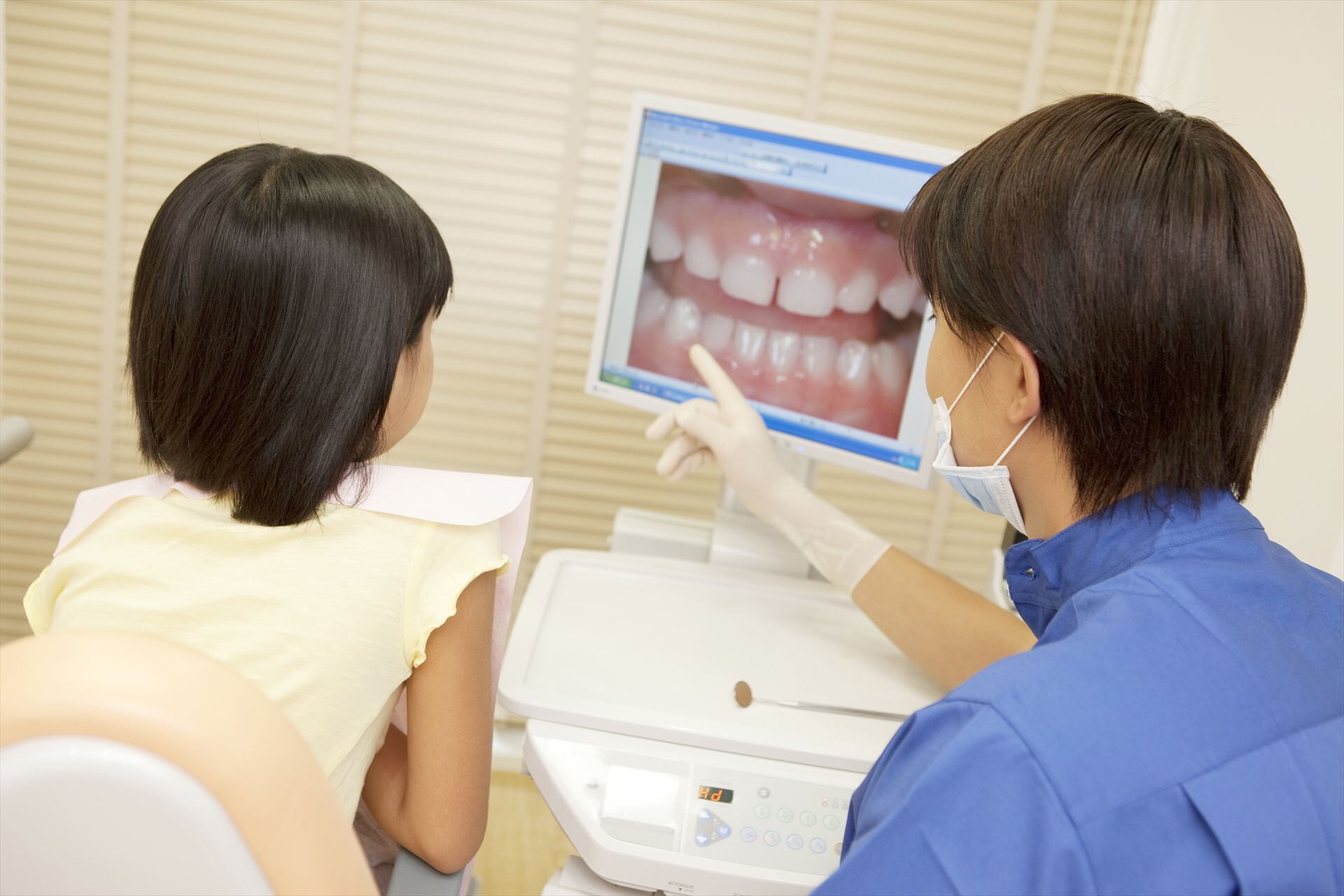 モニターで女の子に治療の説明をする歯科医l